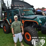John Patterson stands in front of a Green and Orange tricked out Jeep