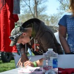 A young man writes a note to a wounded veteran at the 4 Wheel to Heal tent