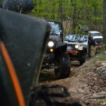 A line of Jeeps makes it's way through a dirt trail in the woods