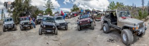Jeeps staged across a large rock posing for a group photo