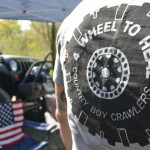 Nathan Ramos wearing a tire design 4Wheel to Heal T-shirt with an American flag in the background