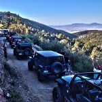 Jeeps stop to take photos of the view on a trail that runs along the side of a mountain